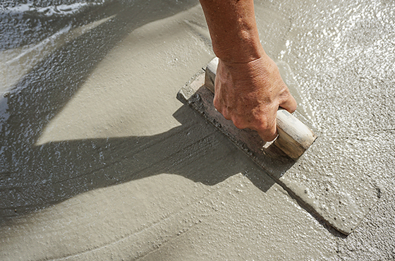 Betonarbeiten in Kellenhusen – Hand glättet frischen Beton.