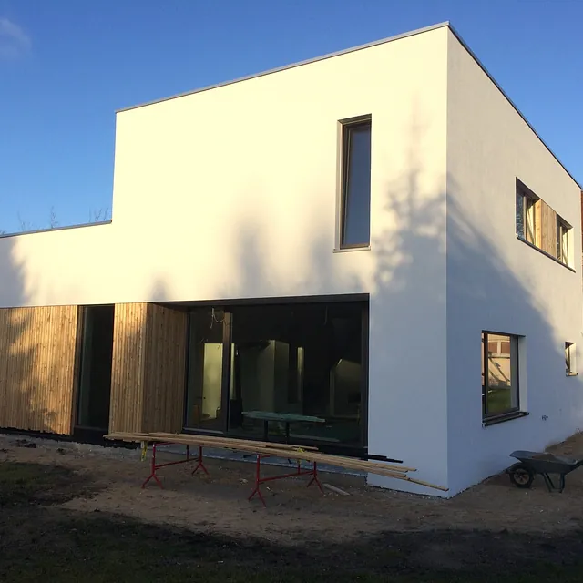 Modernes Einfamilienhaus mit Flachdach, Putzfassade und Holzverkleidung – Bauausführung durch Ewers Bau