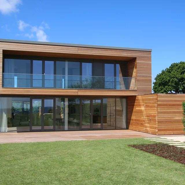 Modernes Einfamilienhaus an der Ostseeküste mit Holzfassade und Balkon – Maurerarbeiten durch Bauunternehmen aus Ostholstein